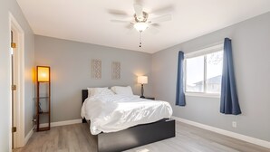 A bedroom with a bed, a ceiling fan, a nightstand, a lamp, a window with curtains, and a wall-mounted shelf. - Spacious 3 BR • Convenient • Big Yard • Office (Kyle)