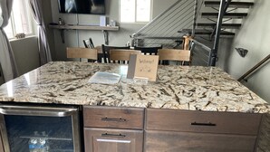 Una cocina con encimera de granito, armarios de madera y lavavajillas de acero inoxidable.