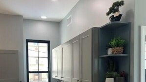Une cuisine dotée d’un plan de travail en bois, de meubles gris, d’un dosseret en carreaux disposés en motif chevron et d’une fenêtre avec des stores.
