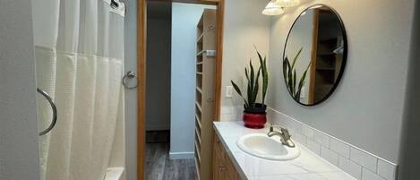Un baño moderno con tragaluz, un espejo grande, un lavamanos y una zona de ducha.