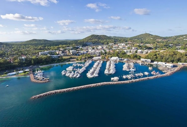 Boats docked in a well-organized marina surrounded by rolling hills and buildings.