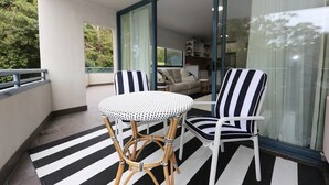 Un balcon avec un sol à rayures, deux chaises et une table.