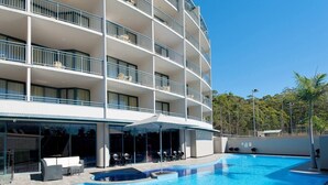 Un hôtel à plusieurs étages doté d’une piscine, d’un espace extérieur aménagé et d’une zone couverte.