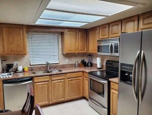 Kitchen features a dishwasher, oven, microwave, and sink with a window above.
