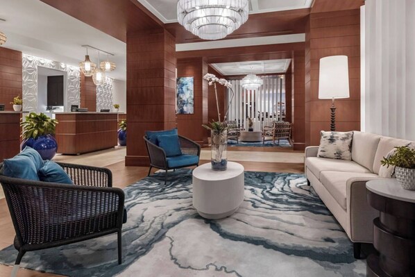 A modern lobby with a reception desk, seating area, and a chandelier. - Marriott Oceana Palms - Luxurious 2-Bedoom - Beachfront resort - Family Friendly (Riviera Beach)