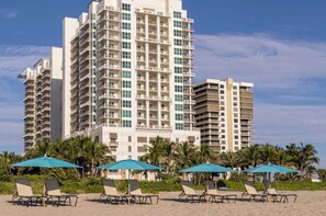 A beachfront hotel with multiple high-rise buildings, beach umbrellas, and lounge chairs. - Marriott Oceana Palms - Luxurious 2-Bedoom - Beachfront resort - Family Friendly (Riviera Beach)