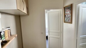 Una cucina con un tavolo di legno, un lampadario, un quadro appeso al muro e una porta che dà su un'altra stanza.