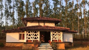 Une maison à deux étages, avec un toit en tuiles, des murs blancs et un porche en bois.