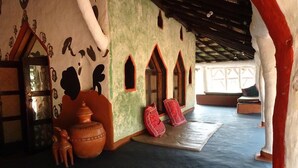 Une pièce traditionnelle avec un plafond bas, un grand pot en argile et un tapis rouge sur le sol.