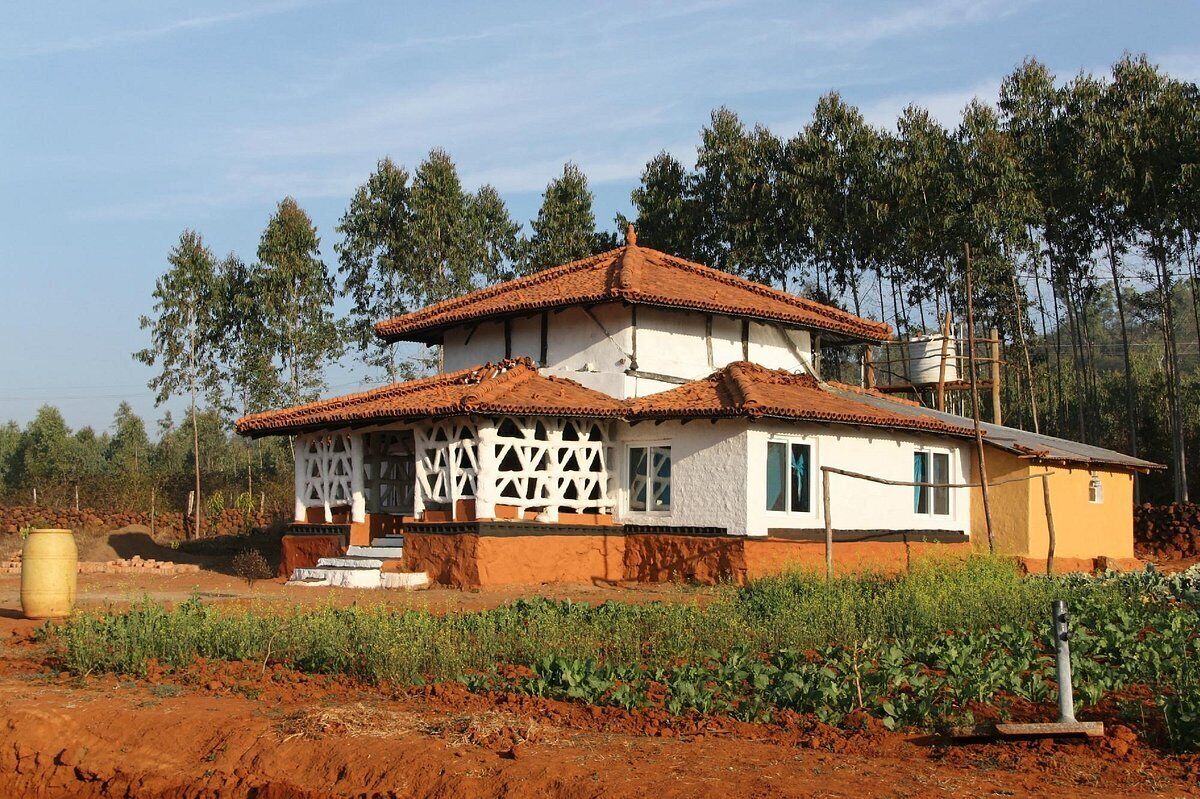 A two-story house with a tiled roof, white walls, and a balcony with lattice railings.