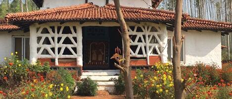 Un edificio tradicional con tejado de baldosas y paredes blancas, rodeado por un jardín con diversas flores.