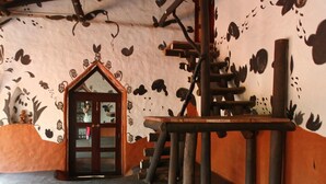 Une pièce avec une structure de jeu en bois, une porte dotée d’un cadre décoratif et un mur orné de motifs géométriques noirs.