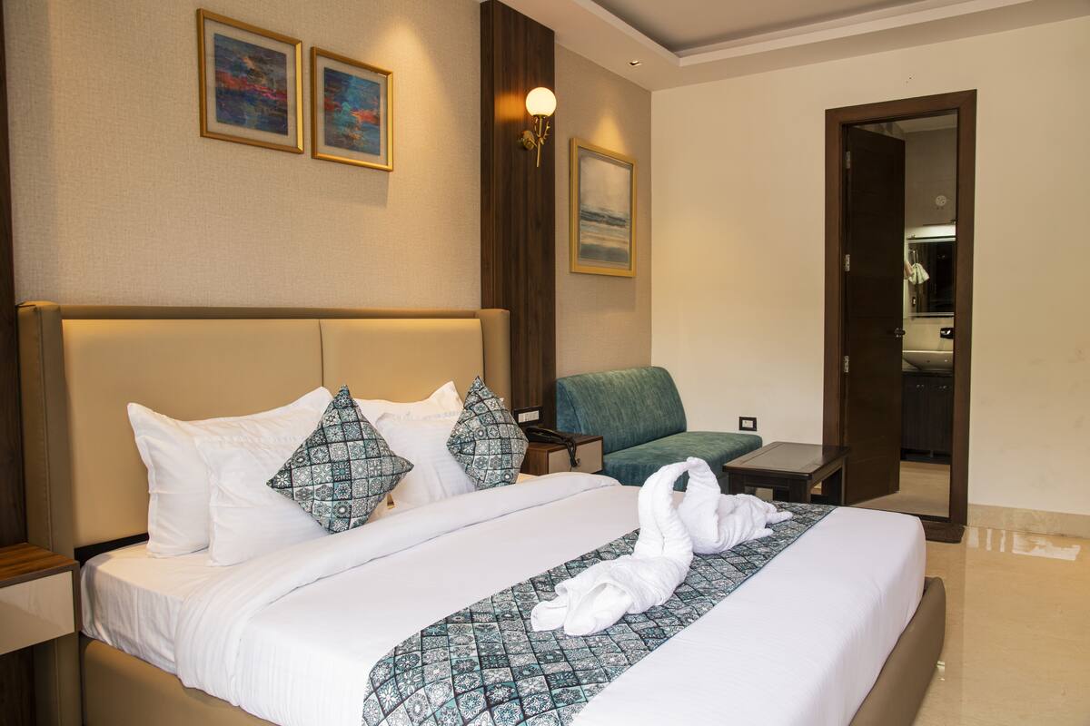 Une chambre d’hôtel avec un grand lit, un bureau, une chaise et un miroir.