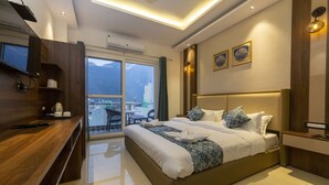 A modern hotel room with a large bed, a desk, and a balcony with a view of the mountains. - Hotel Dream Inn (Narendranagar)