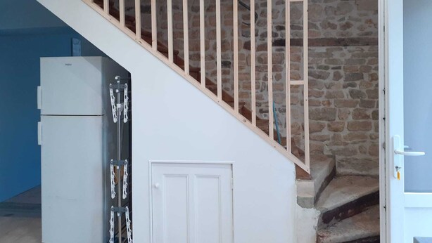 Una escalera con barandillas de madera que lleva a un muro de piedra.