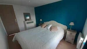 Un dormitorio con una cama, una mesita de noche, un tocador, un espejo y una puerta.