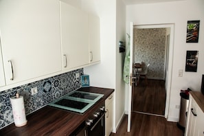 A kitchen with white cabinets, a patterned backsplash, and a modern stove.