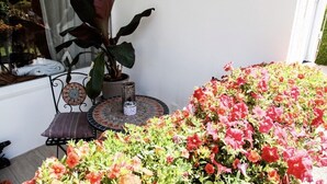 Un petit espace patio avec une table ronde et une chaise, entouré de fleurs aux couleurs vives.