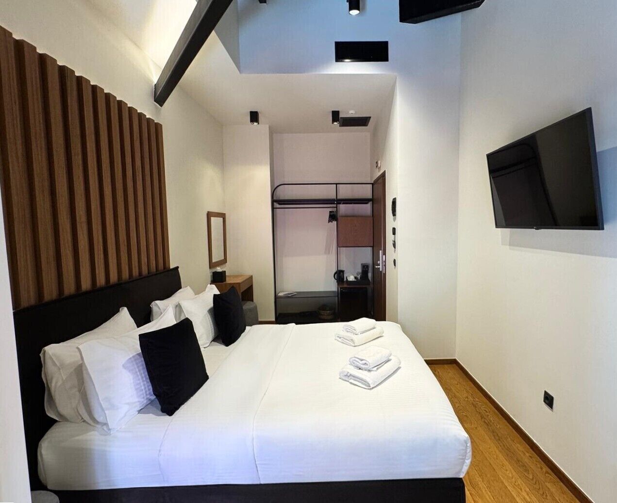 Een moderne hotelkamer met een bed, een televisie, een kledingkast en een douche.
