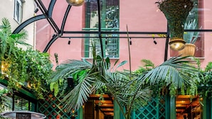 A lush indoor garden with hanging plants and a peacock display. - Mamy Blue Slow Living (Athens)