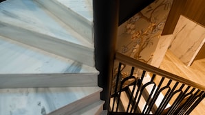 A spiral staircase with white marble steps and a black metal railing. - Mamy Blue Slow Living (Athens)