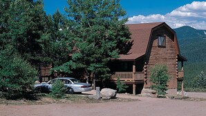 A rustic log cabin with a balcony, surrounded by trees and mountains. - Entire Charming Cabin With Lake And Mountain View (Angel Fire)
