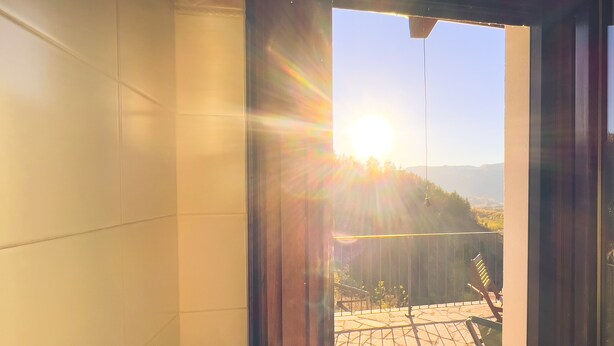 Ein sonnendurchfluteter Raum mit Blick auf einen Balkon und Sitzgelegenheiten im Freien.