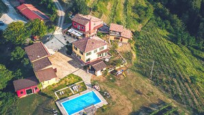 Eine Vogelperspektive auf ein Wohngebiet mit mehreren Häusern, einem Swimmingpool und terrassierten Weinbergen.