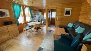 Ein Holzhäuschen-Innenraum mit Essbereich, Sofa und Küche.