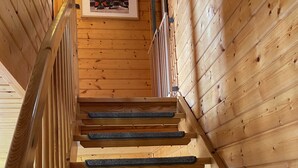 Eine Holztreppe mit Handlauf und einem gerahmten Bild an der Wand darüber.