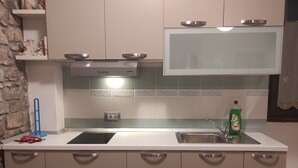 A modern kitchen with a central island, stainless steel appliances, and a backsplash with decorative tiles. - Casa Moratto in the Heart of Buje (Buje)