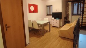 A spacious living area with a dining table, a sofa, a TV, and a staircase. - Casa Moratto in the Heart of Buje (Buje)