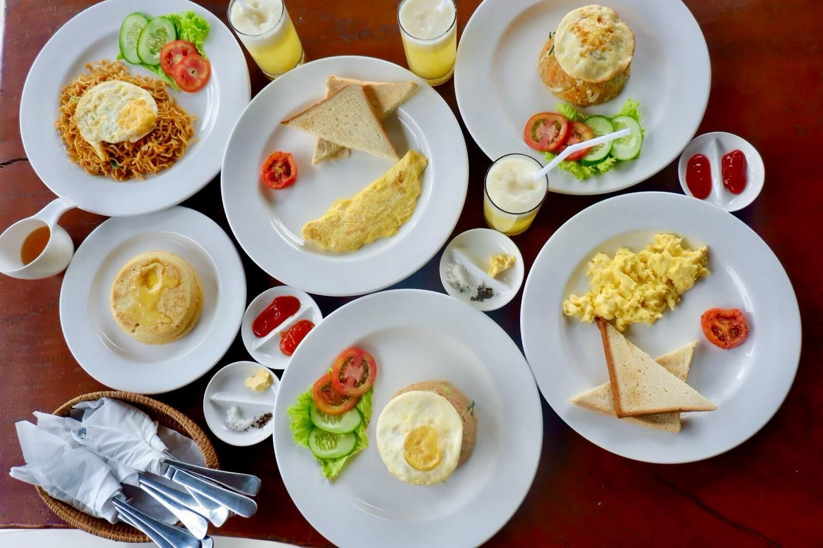 Una mesa con diversos platos de desayuno, incluyendo huevos, tostadas y una variedad de acompañamientos.