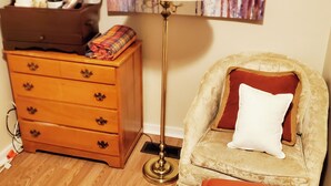 A room with a wooden dresser, a floor lamp, a cushioned armchair, and a small ottoman. - Room-fall Room 3min From Yale, And Other (New Haven)