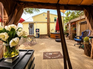 A covered outdoor area with a yellow building in the background, a target on the wall, and a welcome mat on the ground. - Room-cozy Private Room Near Yale Univers (New Haven)