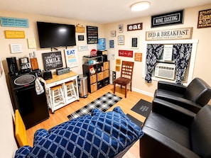 A compact living space with a kitchenette, a dining area, a seating area with a couch, and a TV mounted on the wall. - Room-cozy Private Room Near Yale Univers (New Haven)