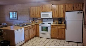A kitchen with wooden cabinets, a white stove, a microwave, and a refrigerator. - Entire Charming Cabin With Lake And Mountain View at Angel Fire (Angel Fire)