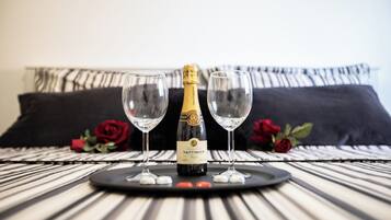 A bottle of Taittinger champagne on a tray with two glasses and rose petals on a striped table.