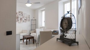 Een woonkamer met een witte bank, een salontafel en een decoratieve vogelkooi.