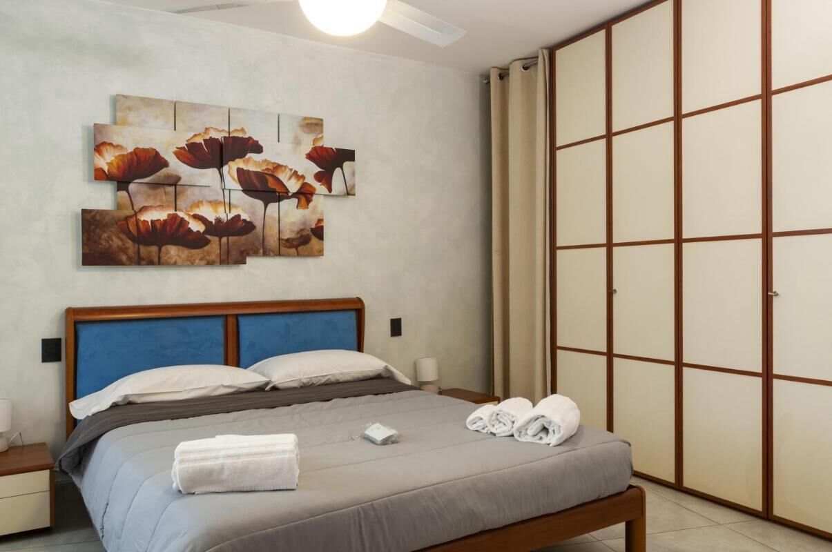 A bedroom with a bed, a nightstand, a wall-mounted artwork, and a sliding door closet.