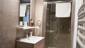 Une salle de bain moderne avec une douche à parois de verre, un lavabo blanc et un miroir au-dessus.