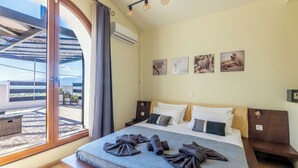 Une chambre avec un grand lit, une vue à travers une porte vitrée et des œuvres d’art accrochées au mur.