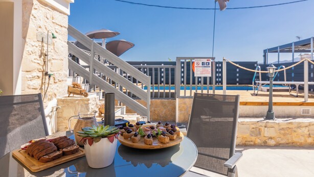 Une table avec un plateau de desserts et une carafe de boissons, donnant sur une piscine et un escalier.