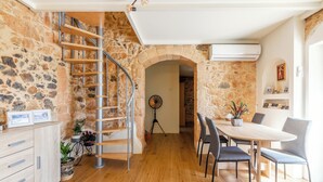 Un espace repas avec une table et des chaises en bois, un escalier avec des rampes en métal et des murs en pierre.