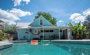 Uma casa com piscina, rede e mobiliário de exterior.