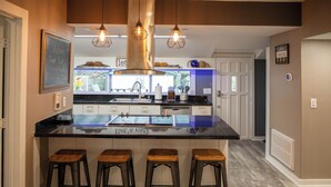 A modern kitchen with a central island, bar stools, pendant lighting, and a chalkboard sign. - Family Home With Private Pool & Yard Only 24 Mi to Disney (St. Cloud)