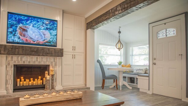 A modern kitchen with a fireplace, a dining area with a bench, and a TV mounted above the fireplace. - Family Home With Private Pool & Yard Only 24 Mi to Disney (St. Cloud)