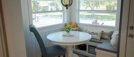 Un espace repas comprenant une table ronde, une chaise, un banc et un luminaire suspendu.
