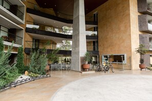 A multi-level atrium with a central open space, potted plants, and bicycles. - Apartasuite A 3 Min Del Aeropuerto Jmc (Rionegro)