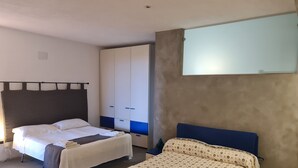 A bedroom with two beds, a wardrobe, and a large mirror.
